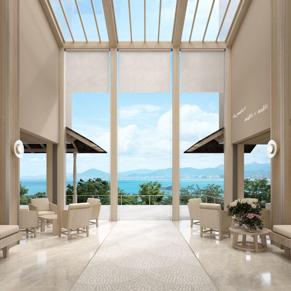 Beachfront wellness resort designed by Openbox Architects featuring a bright open lobby with ocean views, natural light through glass roof, and warm coastal materials.