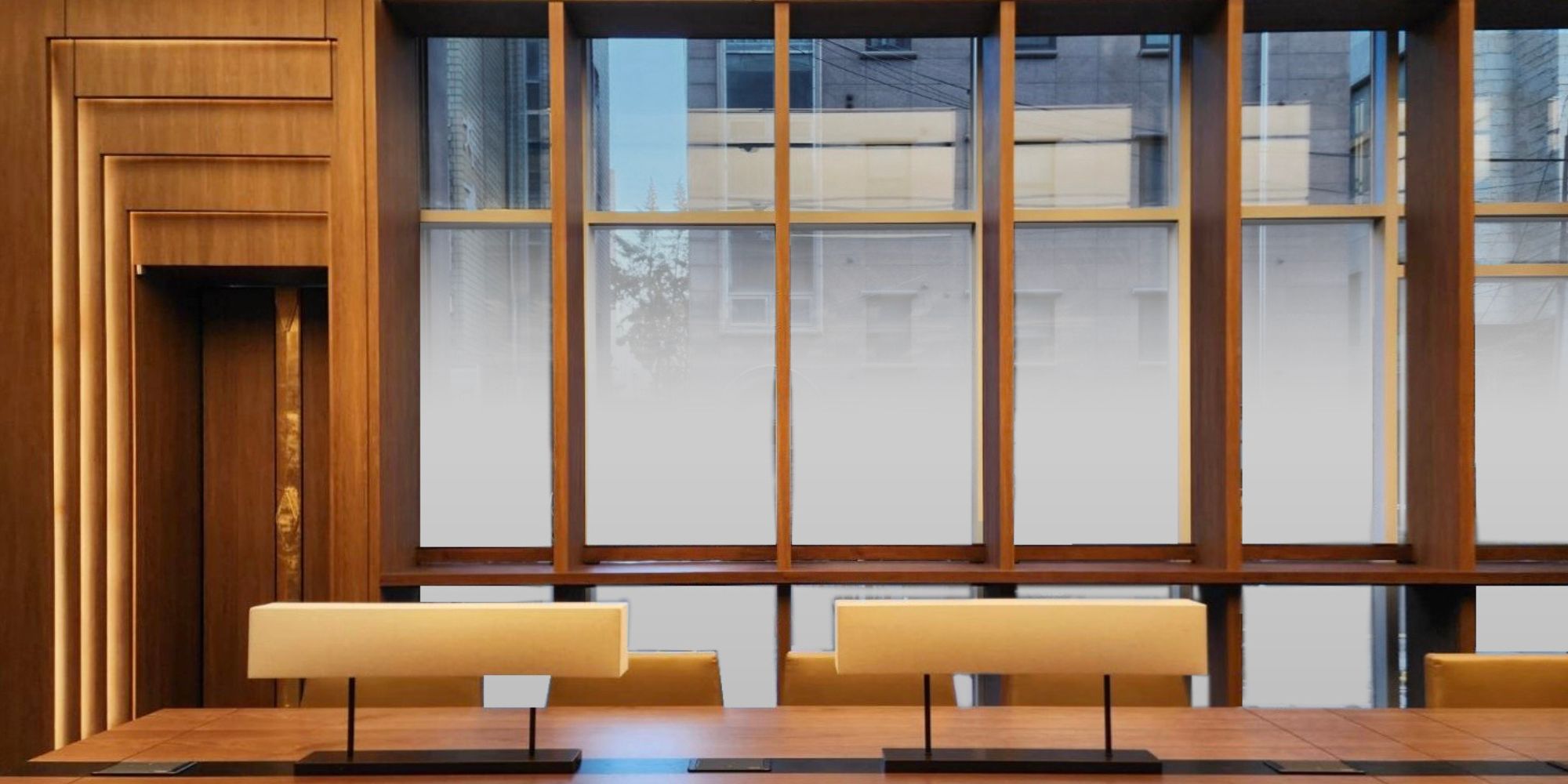 Modern wooden meeting room design in Seoul with warm lighting and large windows.